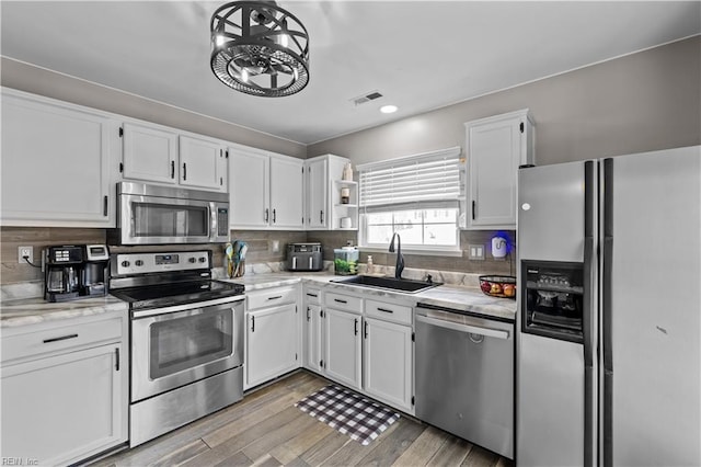 kitchen featuring light wood-type flooring, a sink, open shelves, white cabinetry, and appliances with stainless steel finishes