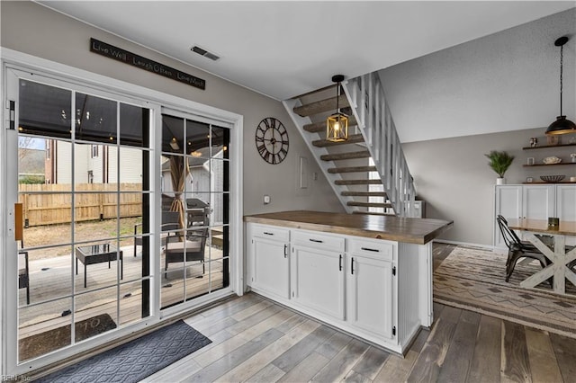 interior space with stairs, wood finished floors, visible vents, and pendant lighting