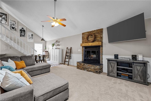 living area with high vaulted ceiling, carpet floors, a fireplace, ceiling fan, and stairs