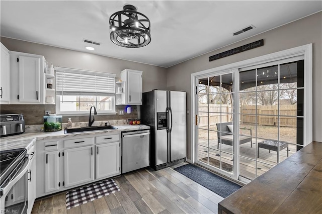 kitchen with visible vents, appliances with stainless steel finishes, open shelves, and a sink