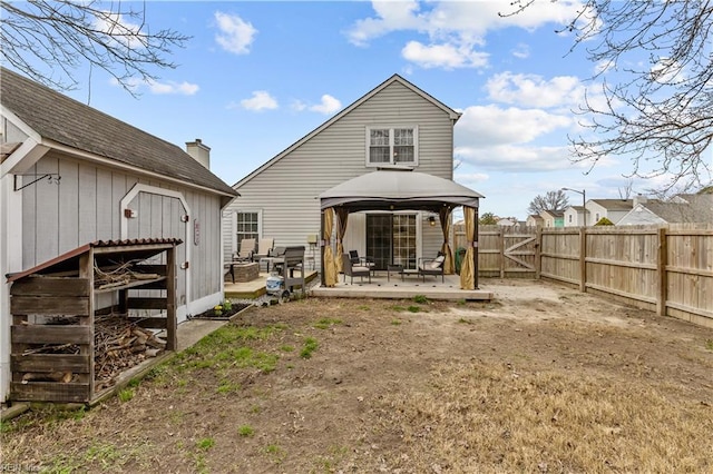 rear view of property featuring a gazebo, fence, and an outdoor structure