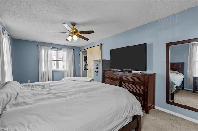 carpeted bedroom with baseboards, ceiling fan, a textured ceiling, and a barn door