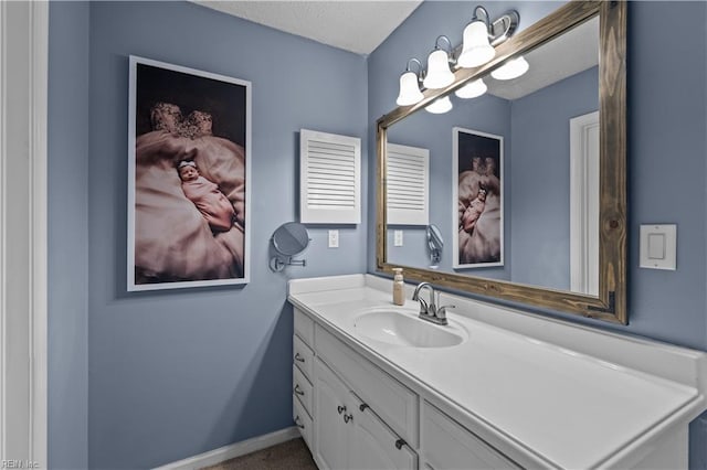 bathroom with a textured ceiling, vanity, and baseboards