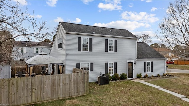 view of front facade with a shingled roof, a front lawn, and fence