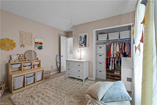 bedroom with a closet, carpet floors, a textured ceiling, and baseboards