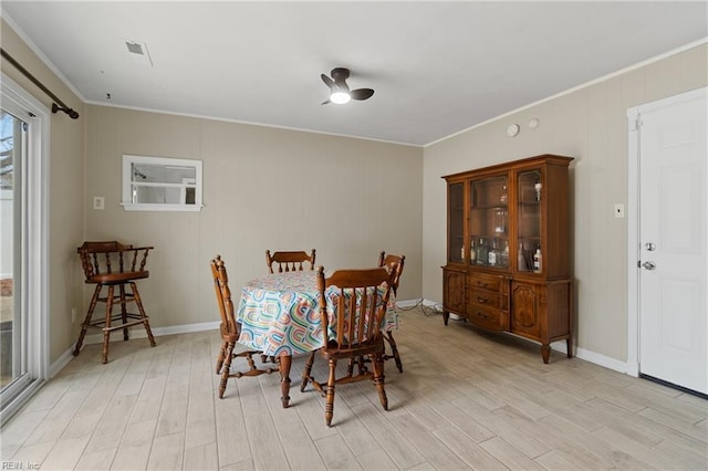 dining space with baseboards, crown molding, and light wood finished floors