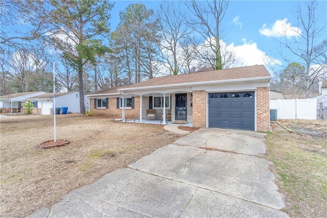 ranch-style home featuring brick siding, fence, concrete driveway, covered porch, and a garage