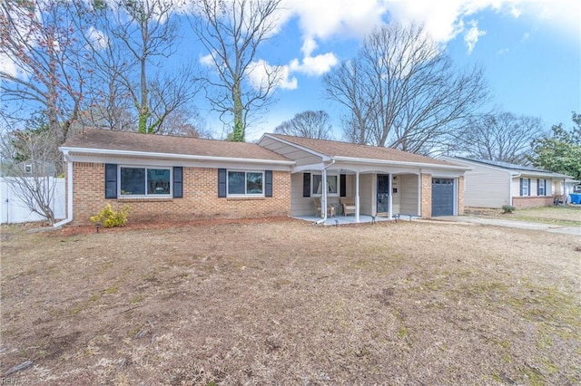 ranch-style home featuring fence, driveway, an attached garage, covered porch, and brick siding