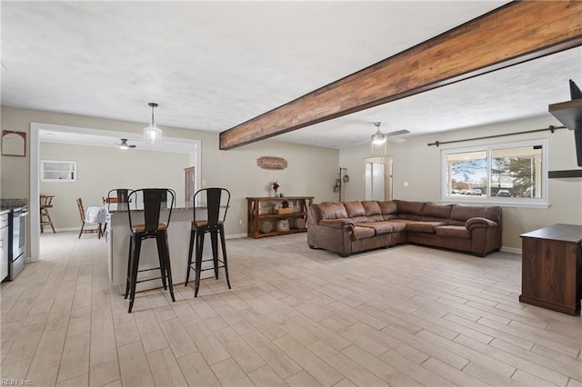 living room featuring baseboards, beam ceiling, a ceiling fan, and light wood finished floors