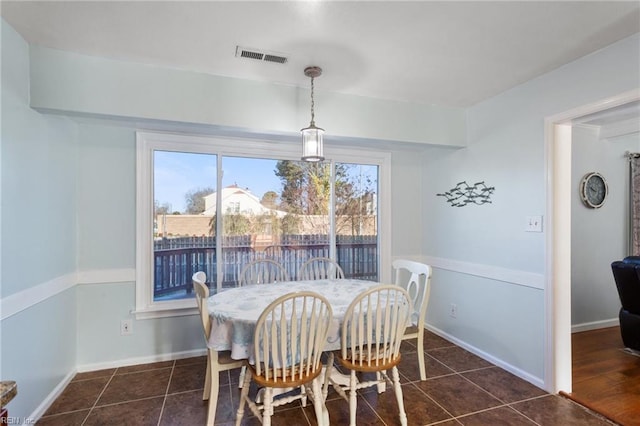 dining space with dark tile patterned flooring, baseboards, and visible vents