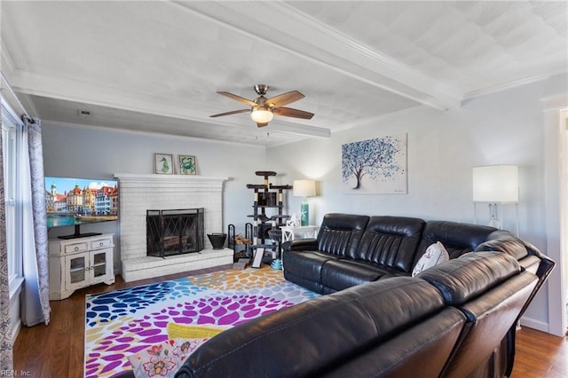 living area with beam ceiling, ornamental molding, wood finished floors, a fireplace, and ceiling fan