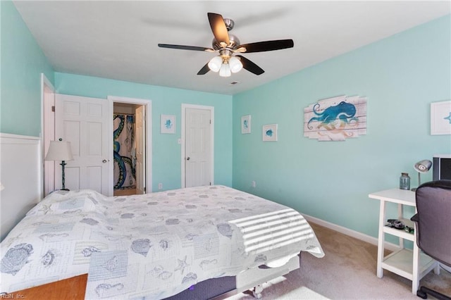 bedroom with a spacious closet, baseboards, carpet flooring, a closet, and a ceiling fan