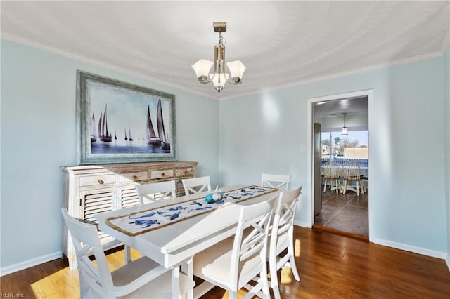 dining space featuring baseboards, a notable chandelier, and wood finished floors