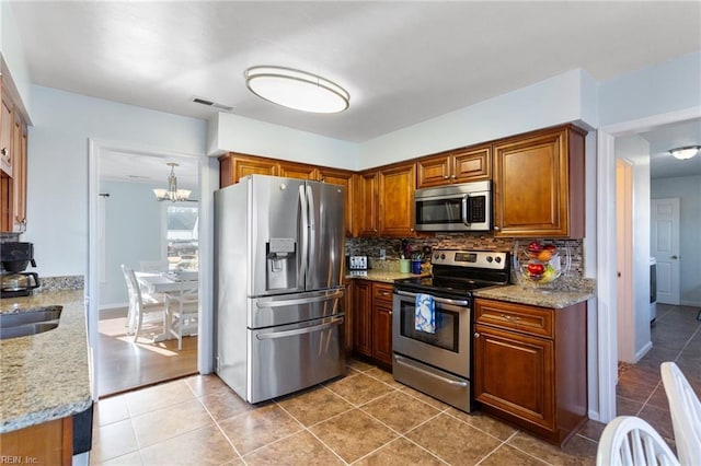 kitchen with brown cabinetry, visible vents, backsplash, and stainless steel appliances