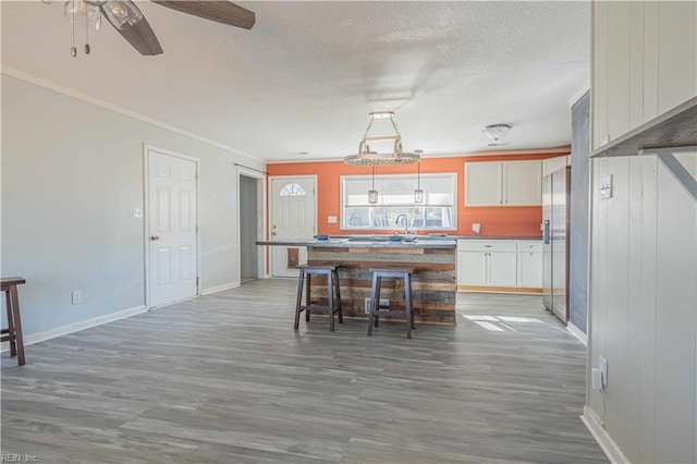 kitchen with a center island, stainless steel fridge with ice dispenser, wood finished floors, a textured ceiling, and white cabinetry