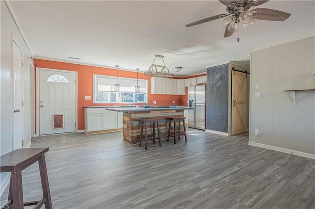 unfurnished dining area featuring a ceiling fan, a barn door, wood finished floors, and a sink