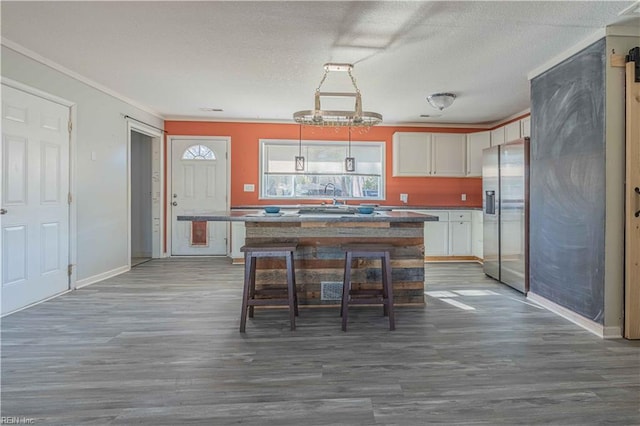 kitchen with a kitchen island, stainless steel refrigerator with ice dispenser, dark wood-style floors, a textured ceiling, and a sink