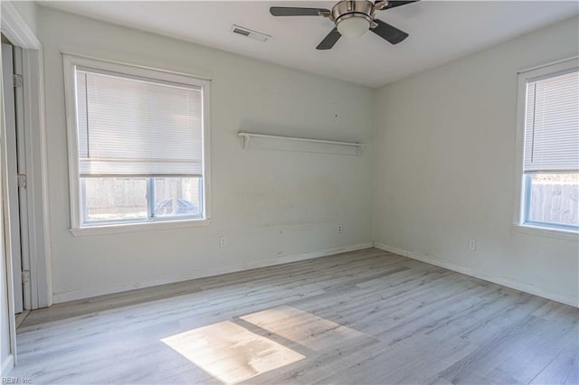 empty room with wood finished floors, a healthy amount of sunlight, and visible vents