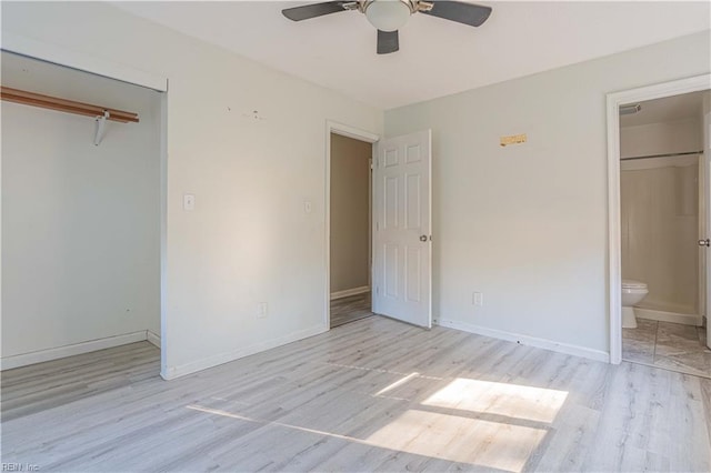 unfurnished bedroom with a ceiling fan, wood finished floors, connected bathroom, a closet, and baseboards