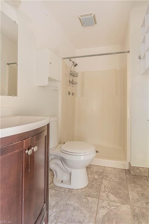 bathroom featuring visible vents, toilet, vanity, and walk in shower