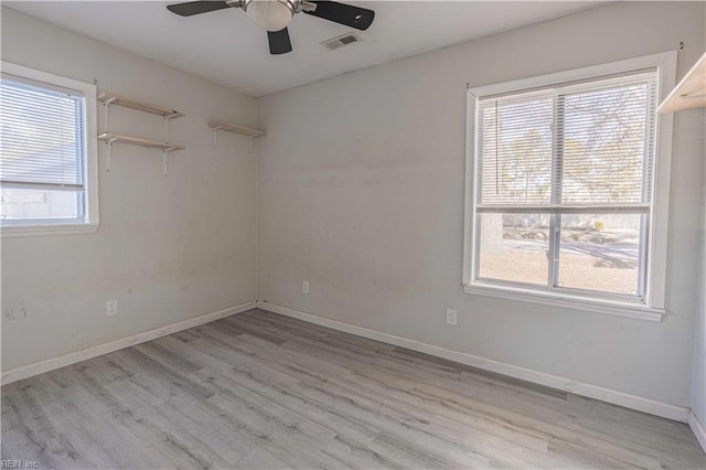 spare room with visible vents, ceiling fan, baseboards, and wood finished floors