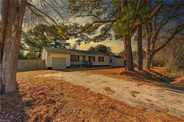 ranch-style home featuring driveway, an attached garage, and fence