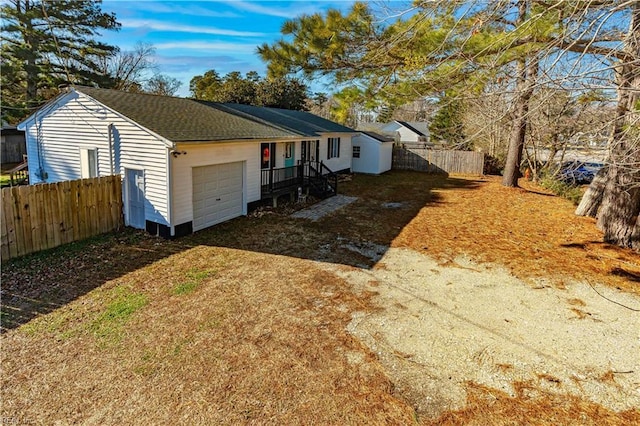 exterior space featuring driveway, roof with shingles, a garage, and fence