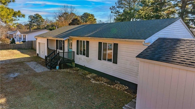 view of front of home featuring roof with shingles and fence