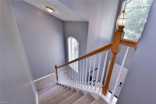 staircase featuring baseboards and carpet floors