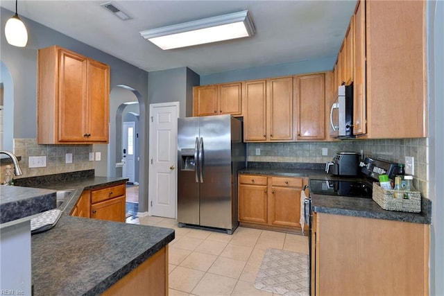 kitchen with visible vents, light tile patterned floors, appliances with stainless steel finishes, arched walkways, and a sink