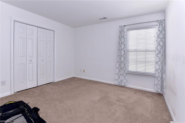 unfurnished bedroom with a closet, visible vents, baseboards, and carpet