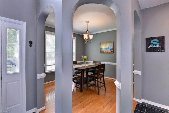 dining area featuring arched walkways, crown molding, baseboards, and wood finished floors