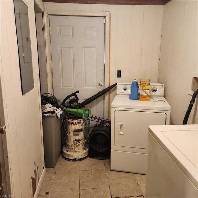 washroom featuring washer and dryer, laundry area, electric panel, and wood walls