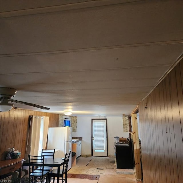 dining area featuring ceiling fan and wood walls