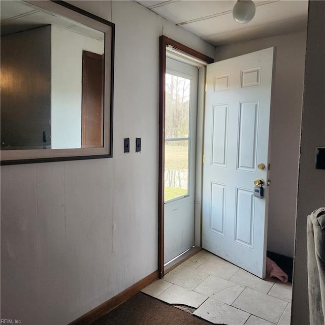 entryway with a wealth of natural light, light tile patterned floors, and baseboards