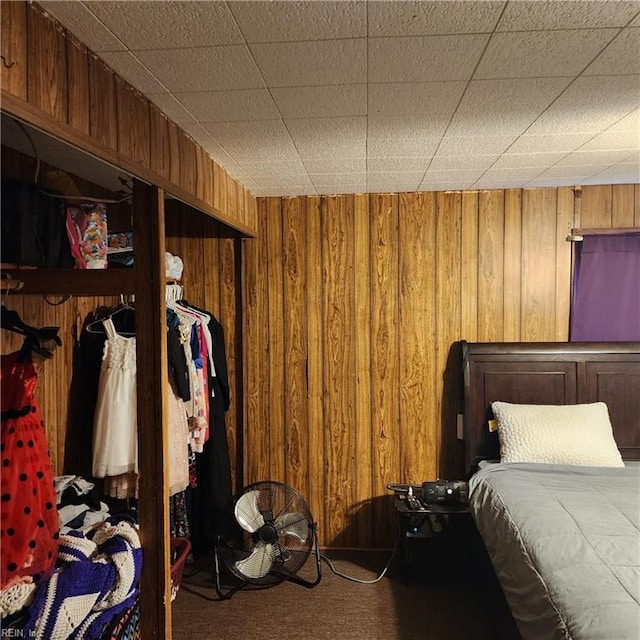 carpeted bedroom with a closet and wooden walls