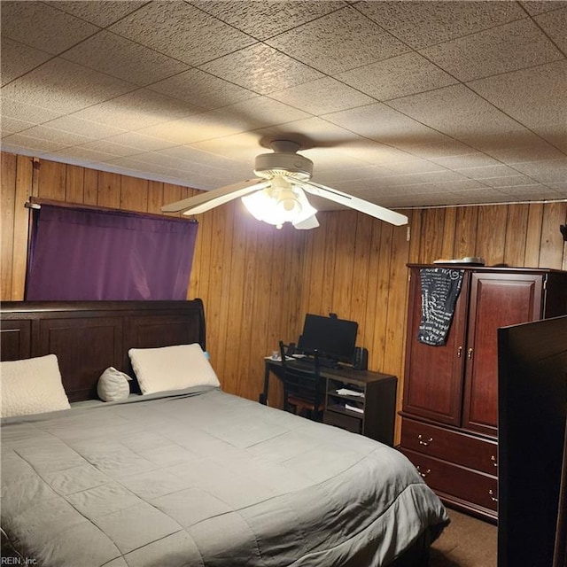 bedroom featuring ceiling fan and wood walls