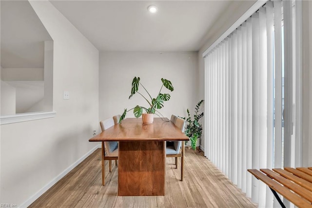 dining area with baseboards and light wood finished floors