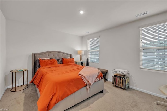 carpeted bedroom with visible vents, multiple windows, and baseboards