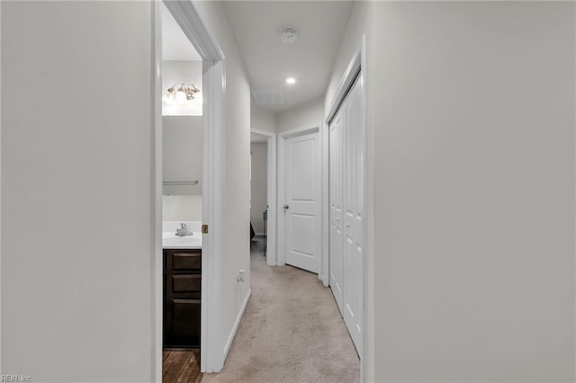 corridor featuring visible vents, baseboards, and light carpet