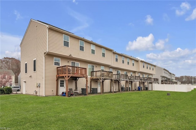 rear view of property with a lawn, central AC unit, and fence