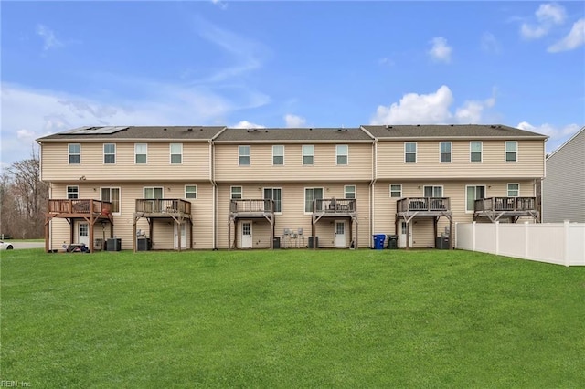 back of property with a lawn, central AC, and fence