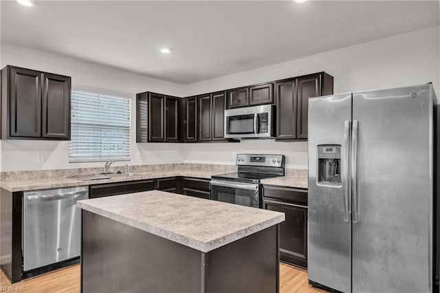 kitchen with light wood finished floors, a kitchen island, stainless steel appliances, and light countertops