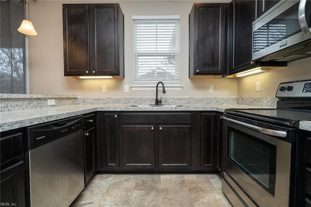 kitchen featuring hanging light fixtures, appliances with stainless steel finishes, light countertops, and a sink