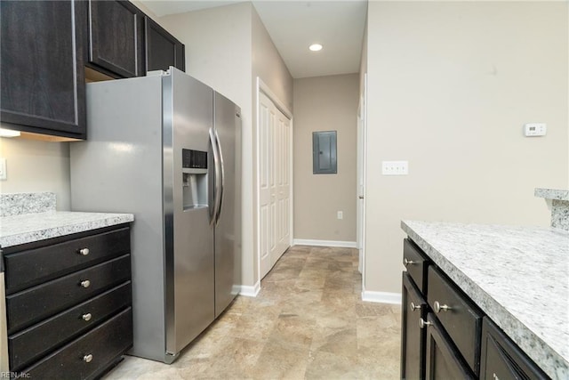 kitchen with baseboards, light countertops, electric panel, stainless steel refrigerator with ice dispenser, and dark cabinets