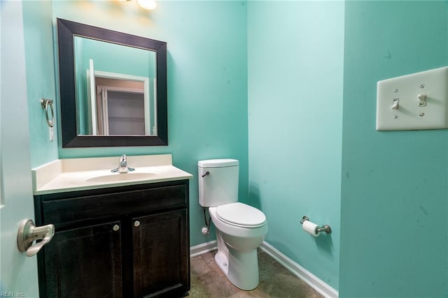 half bathroom featuring vanity, toilet, and baseboards