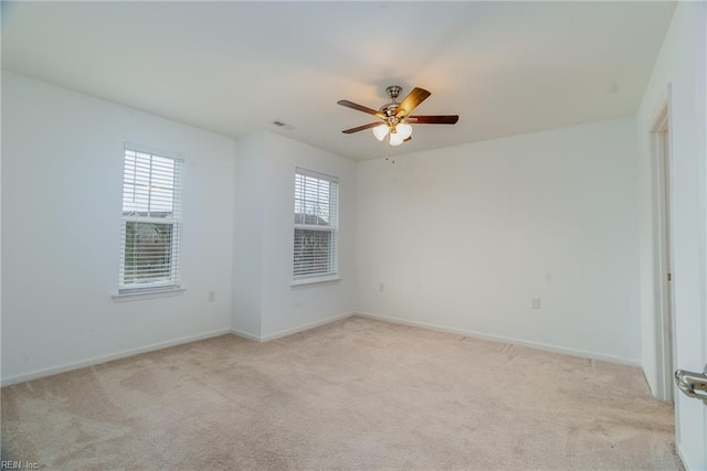 empty room with visible vents, a ceiling fan, baseboards, and light carpet