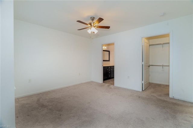 unfurnished bedroom with baseboards, light carpet, and a spacious closet