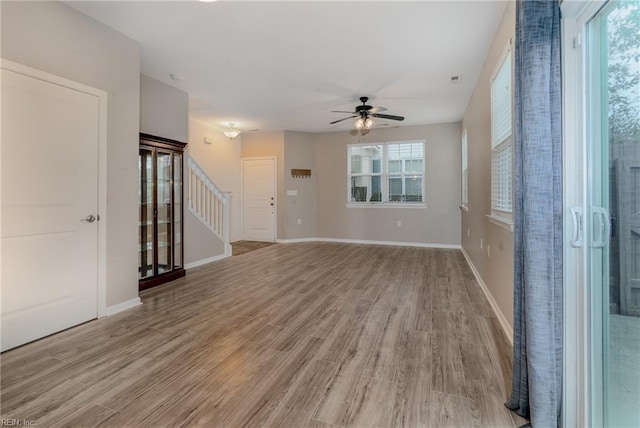 empty room featuring a ceiling fan, light wood-style floors, and baseboards