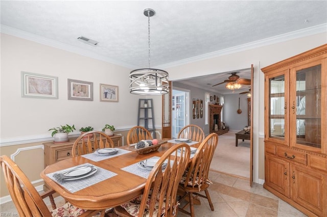 dining room featuring visible vents, a textured ceiling, a brick fireplace, and crown molding